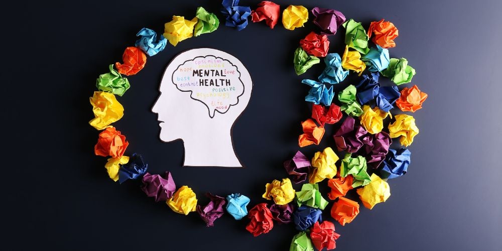 Picture of a head surrounded by colorful paper representing mental health funding benefits.