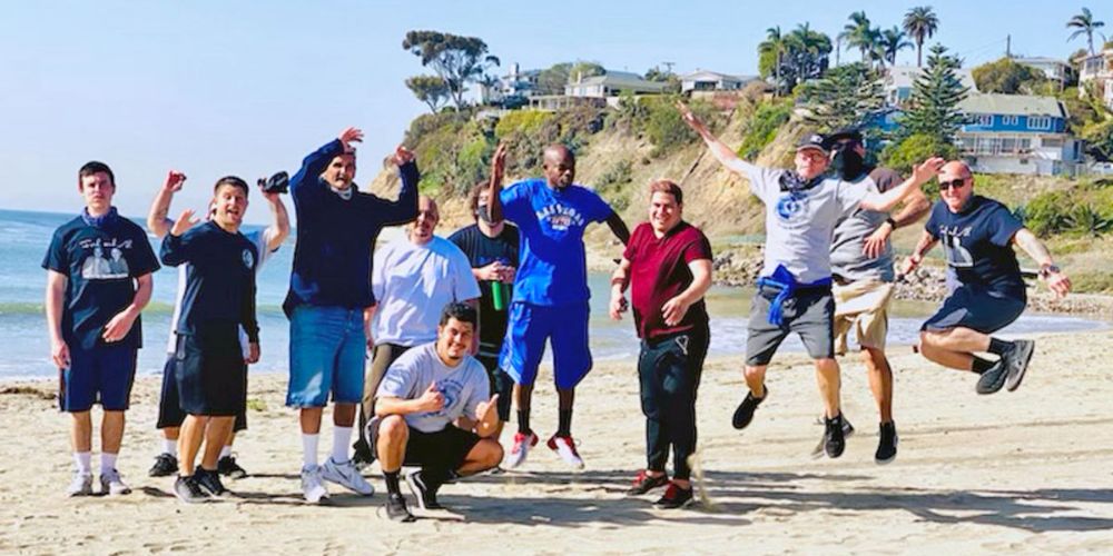 A group of Fred Brown Recovery Service clients celebrate their addiction recovery program on a beach.